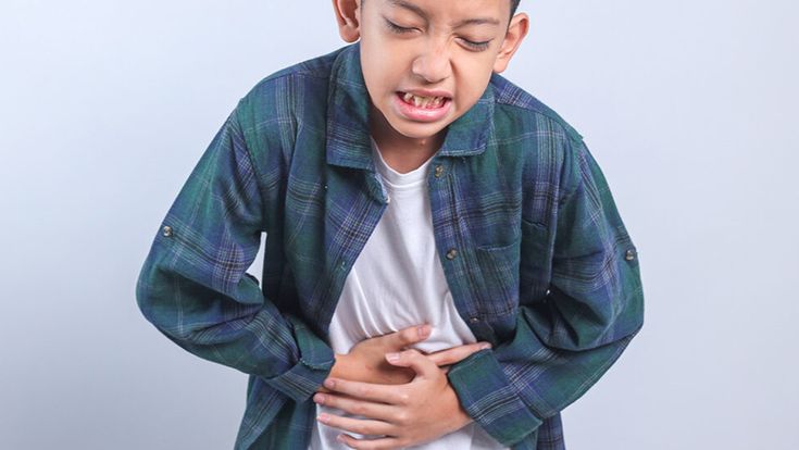 Child holding stomach in pain indicating possible gastrointestinal discomfort.