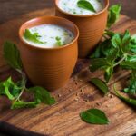 Glass of traditional pink Solkadhi made with kokum and coconut milk, served beside dried kokum on a wooden table, highlighting its digestive and probiotic benefits.